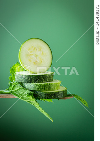 Raw organic zucchini slices with leaves on soft mint green background 141489371