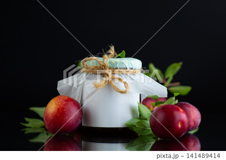 Homemade plum jam in glass jar with fresh fruits on black background Homemade plum jam in glass jar with fresh fruits on black background 141489414