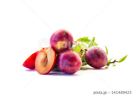 Seasonal ripe plum harvest with fresh leaves on white background Seasonal ripe plum harvest with fresh leaves on white background 141489425