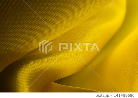 Macro shot of vibrant yellow satin fabric with gentle folds, soft lighting, and smooth texture 141489686