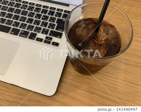アイスコーヒーとノートパソコンのあるカフェのワークスペース アイスコーヒーとノートパソコンのあるカフェのワークスペース 141490497