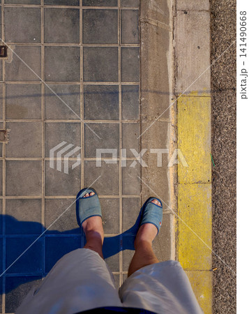 Casual person standing on a tiled city sidewalk Casual person standing on a tiled city sidewalk 141490668
