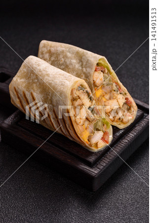 Grilled chicken shawarma or doner with tomatoes, cucumber, and sauces, takeout food Grilled chicken shawarma or doner with tomatoes, cucumber, and sauces, takeout food 141491513