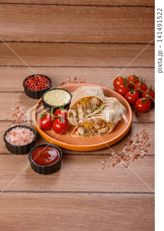 Grilled chicken shawarma or doner with tomatoes, cucumber, and sauces, takeout food Grilled chicken shawarma or doner with tomatoes, cucumber, and sauces, takeout food 141491522