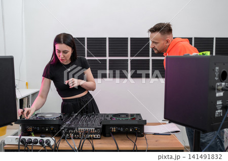 DJ student learning track mixing techniques in studio with hands-on equipment guidance. DJ, student, track mixing, equipment, learning DJ student learning track mixing techniques in studio with hands-on equipment guidance. DJ, student, track mixing, equipment, learning 141491832