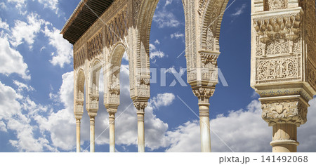 Arches in Islamic (Moorish) style (against the background of a beautiful sky with clouds) in Alhambra, Granada, Spain Arches in Islamic (Moorish) style (against the background of a beautiful sky with clouds) in Alhambra, Granada, Spain 141492068