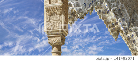 Arches in Islamic (Moorish) style (against the background of a beautiful sky with clouds) in Alhambra, Granada, Spain 141492071