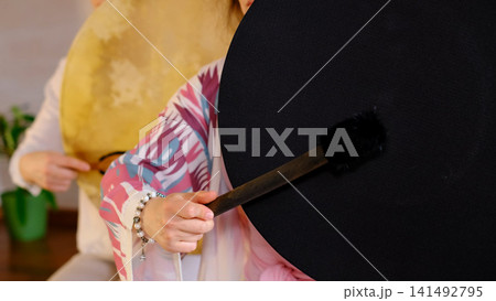 Close up of two women holding large frame drums, with a black drum and soft mallet filling the foreground. Drum meditation and sound healing support grounding, stress relief, and focus. Close up of two women holding large frame drums, with a black drum and soft mallet filling the foreground. Drum meditation and sound healing support grounding, stress relief, and focus. 141492795