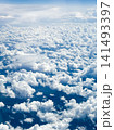 Many fluffy clouds scattered across blue sky during daylight top view from plane flying at high altitude. Clouds vary in size and shape, creating soft texture against vibrant blue background 141493397