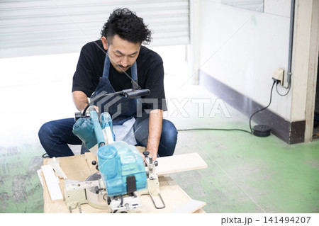 DIY・木工でスライド丸ノコを使って木材加工する男性職人 電動工具によるの家具製作の日曜大工など DIY・木工でスライド丸ノコを使って木材加工する男性職人 電動工具によるの家具製作の日曜大工など 141494207
