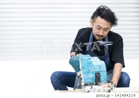 DIY・木工でスライド丸ノコを使って木材加工する男性職人 顔無しの手元のクローズアップ DIY・木工でスライド丸ノコを使って木材加工する男性職人 顔無しの手元のクローズアップ 141494214