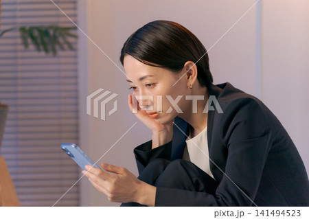 ボーッとスマホを見る女性 ボーッとスマホを見る女性 141494523