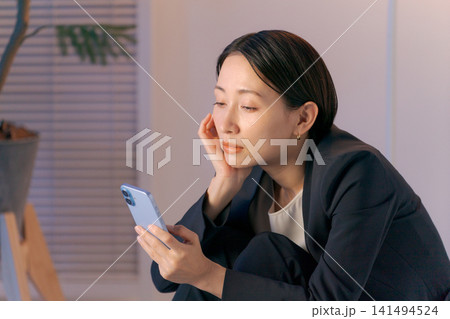 ボーッとスマホを見る女性 ボーッとスマホを見る女性 141494524