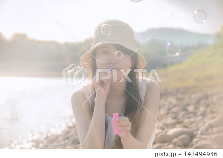 光あふれる中でシャボン玉を飛ばす白ワンピースの女性 光あふれる中でシャボン玉を飛ばす白ワンピースの女性 141494936