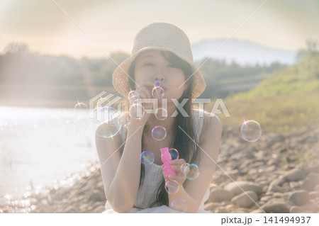夏の水辺でシャボン玉を吹く女性 夏の水辺でシャボン玉を吹く女性 141494937