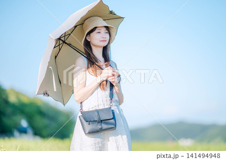 夏の草原で日傘をさして微笑む女性 夏の草原で日傘をさして微笑む女性 141494948