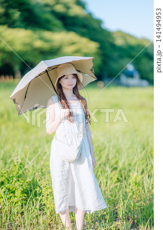 新緑の草原で日傘をさす白ワンピースの女性 新緑の草原で日傘をさす白ワンピースの女性 141494953