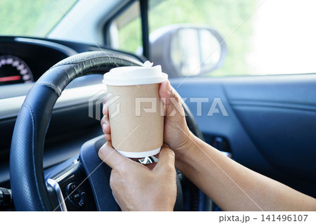 Bangkok, Thailand March 16, 2025 Asian woman driver hold coffee cup for drink in car. Bangkok, Thailand March 16, 2025 Asian woman driver hold coffee cup for drink in car. 141496107