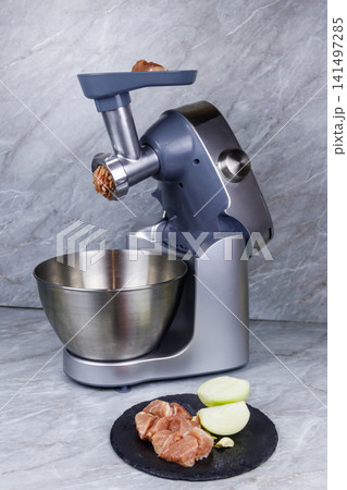 Electric eat grinder and fresh meat on kitchen table. Preparation of minced meat Electric eat grinder and fresh meat on kitchen table. Preparation of minced meat 141497285