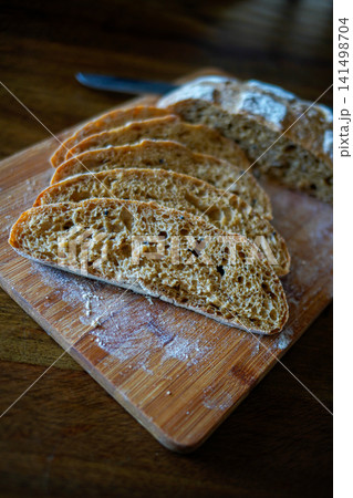 Close-up of homemade sourdough artisan bread showing airy crumb texture on wooden board with flour. Rustic bakery style, natural light, organic food concept. Close-up of homemade sourdough artisan bread showing airy crumb texture on wooden board with flour. Rustic bakery style, natural light, organic food concept. 141498704
