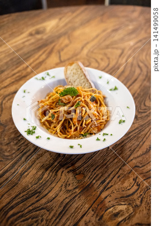 Fresh Spaghetti Marinara with Parmesan Cheese and Artisan Bread on Rustic Wooden Restaurant Table 141499058