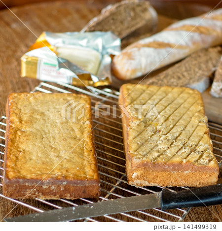 Fresh Homemade Loaf Cakes Cooling on Wire Rack with Rustic Bread Butter and Wooden Table Flat Lay 141499319