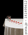 Still life with a glass beaker of water and red teaspoons on a table 141499412