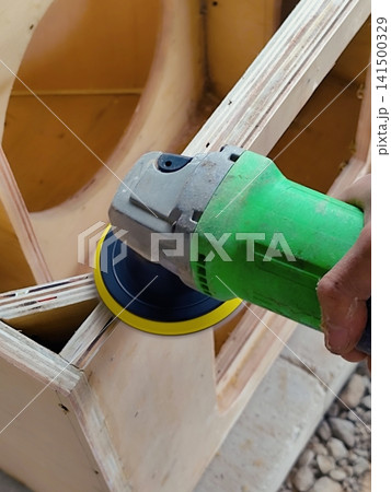 A carpenter is sanding a wooden board with an electric machine A carpenter is sanding a wooden board with an electric machine 141500329