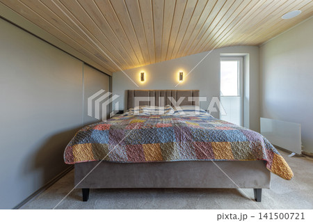 Bedroom Interior with Double Bed and Sloped Wooden Ceiling Bedroom Interior with Double Bed and Sloped Wooden Ceiling 141500721