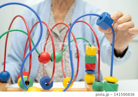 Asian elderly woman playing enhancing skill board game. Asian elderly woman playing enhancing skill board game. 141500836