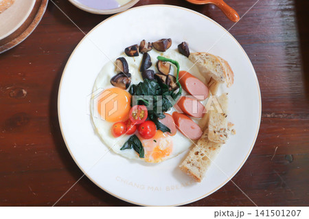 fried egg or sunny side up egg with vegetable topping and bread or breakfast fried egg or sunny side up egg with vegetable topping and bread or breakfast 141501207