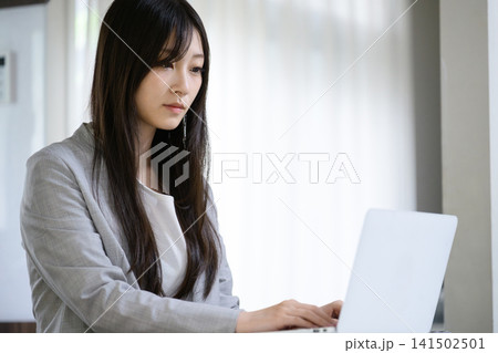 リビングでノートパソコンを操作する日本人女性 リビングでノートパソコンを操作する日本人女性 141502501