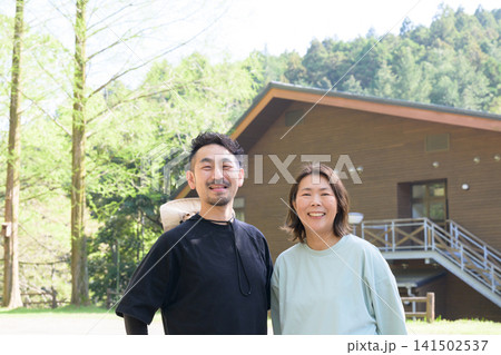 ペンション前に立つ笑顔の夫婦オーナー 141502537