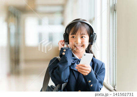 学校の廊下でヘッドフォンで音楽を聴く制服姿の小学生,中学生,高校生の女の子 学校の廊下でヘッドフォンで音楽を聴く制服姿の小学生,中学生,高校生の女の子 141502731