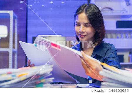 Young Asian businesswoman reviewing documents while working in office Young Asian businesswoman reviewing documents while working in office 141503026