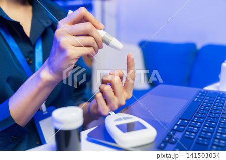 Young Asian woman checking blood sugar level with glucose meter Young Asian woman checking blood sugar level with glucose meter 141503034