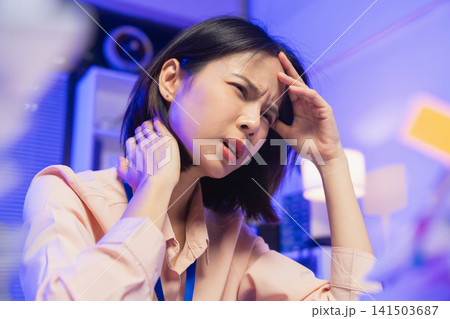 Stressed young Asian office worker feeling overwhelmed with paperwork and workload while working on laptop in office. Stressed young Asian office worker feeling overwhelmed with paperwork and workload while working on laptop in office. 141503687