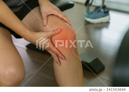 Woman holding painful knee after workout at gym Woman holding painful knee after workout at gym 141503694