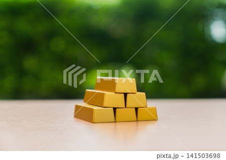 Stack of gold bars on table with green background. Stack of gold bars on table with green background. 141503698
