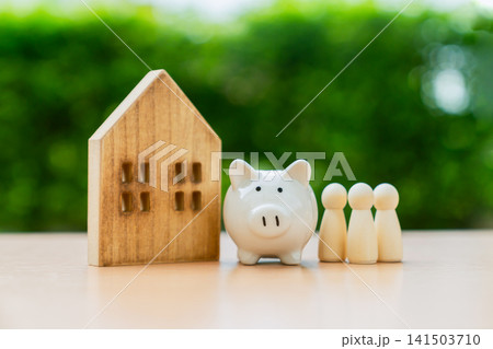 Wooden house with piggy bank and family figures, financial wellbeing, and future planning. Wooden house with piggy bank and family figures, financial wellbeing, and future planning. 141503710
