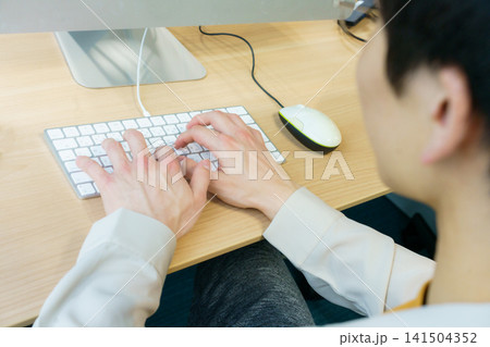デスクトップパソコンで入力作業をする若い日本人男性の手元 141504352