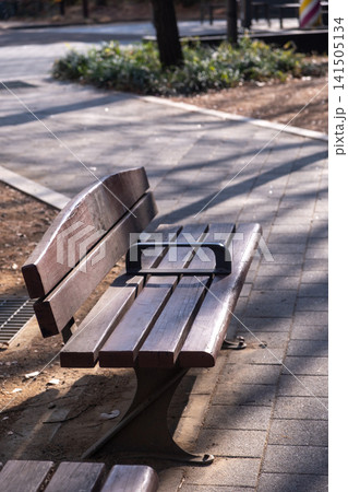 Close up of wooden bench, with pathway on the background in public park Close up of wooden bench, with pathway on the background in public park 141505134