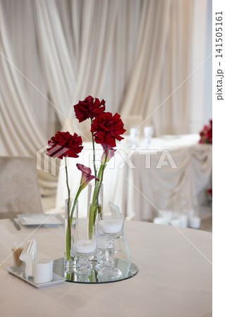 Elegant wedding reception table decoration featuring red roses and candles Elegant wedding reception table decoration featuring red roses and candles 141505161