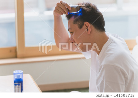 電気ブラシで頭皮をケアする40代男性 電気ブラシで頭皮をケアする40代男性 141505718