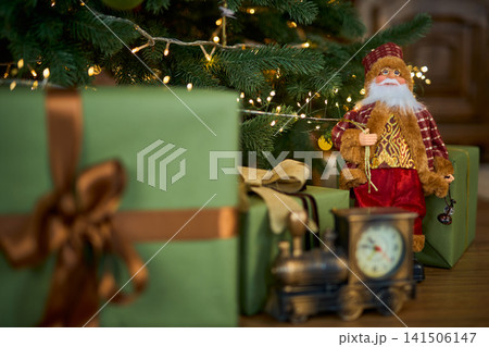Santa Claus Figurine and Vintage Toy Train Near a Christmas Tree 141506147