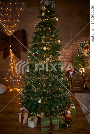Fully Decorated Christmas Tree with Wrapped Gifts and Fairy Lights 141506156