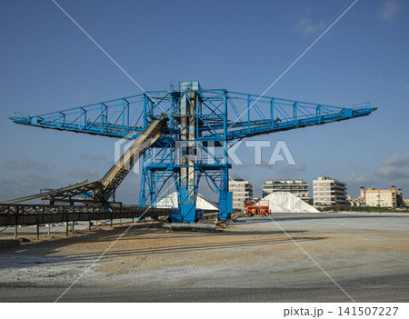 Large salt harvesting conveyor structure near salt piles and buildings in Santa Pola Large salt harvesting conveyor structure near salt piles and buildings in Santa Pola 141507227