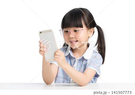Asian little girl wearing glasses using smartphone isolated on white background, child screen time and eyesight health concept Asian little girl wearing glasses using smartphone isolated on white background, child screen time and eyesight health concept 141507773