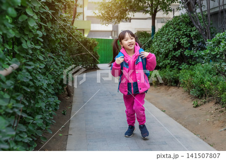 Smiling Asian little girl holding smartphone during outdoor picnic in park, cheerful child lifestyle concept, family leisure and technology use 141507807