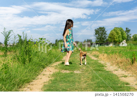 Asian little girl running with dog on grassy path under blue sky, joyful childhood outdoor activity and freedom concept Asian little girl running with dog on grassy path under blue sky, joyful childhood outdoor activity and freedom concept 141508270